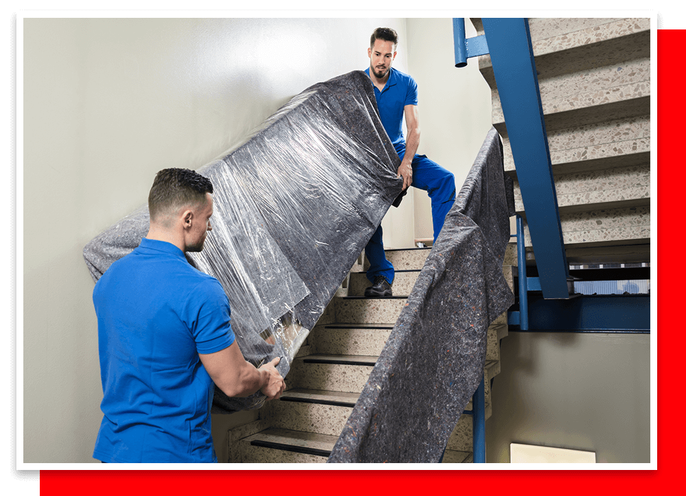 two movers carrying a couch down a stairwell